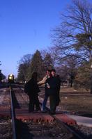 Three Students Standing on the Train Tracks with an Oncoming Train Behind them